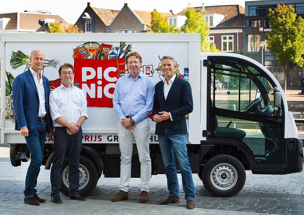 The Picnic founders standing in front of an electric Picnic delivery vehicle.