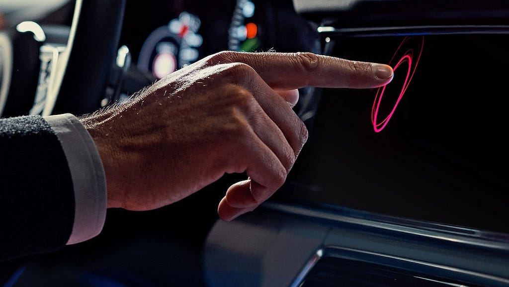 A hand touching the infotainment system in a Porsche sportscar.
