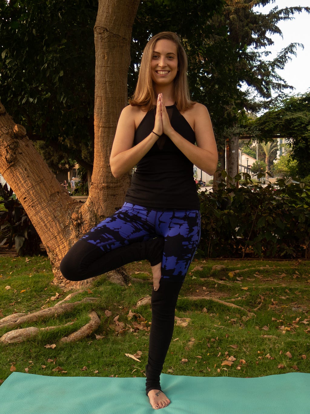 A woman balances on her left foot, with her hands in prayer position and the sole of her right foot against her left thigh.