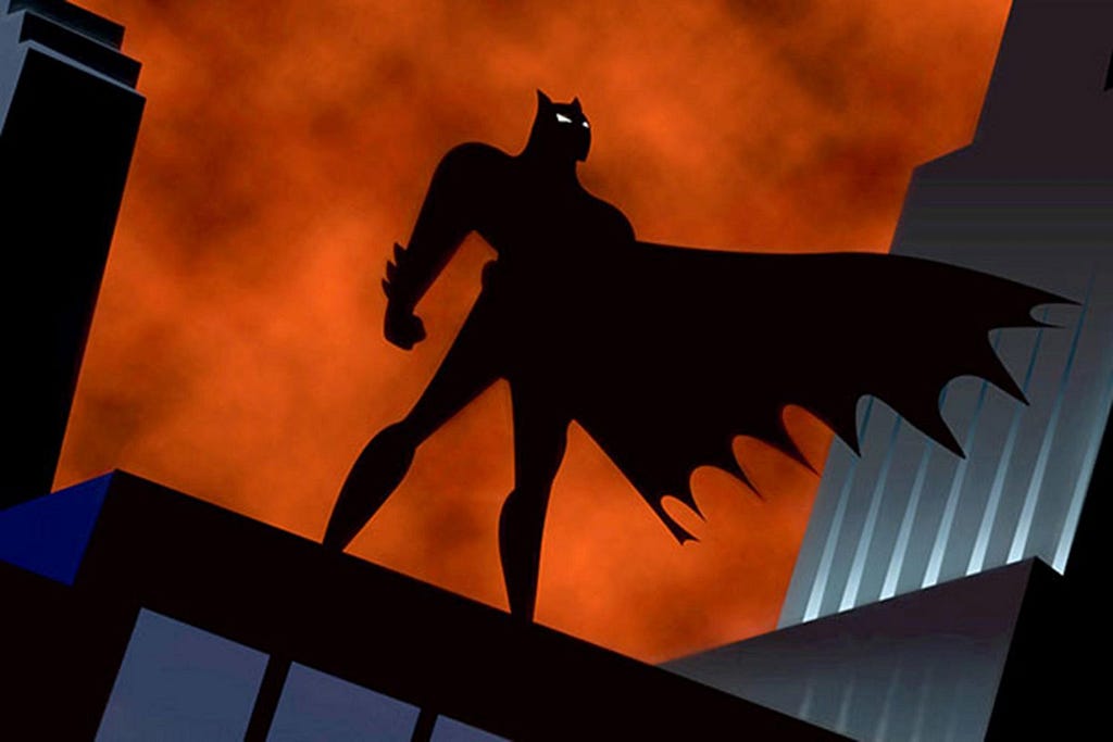 The silhouette of an animated Batman against a fiery orange sky