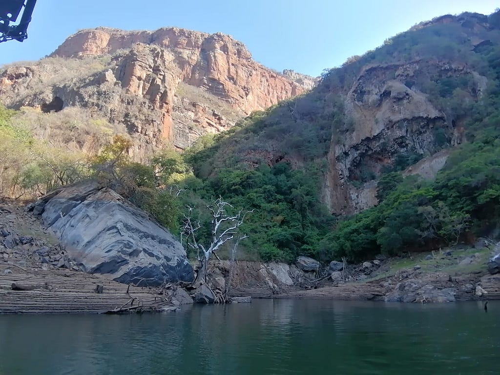 A mountain side with a skull staring back and a dam in the foreground