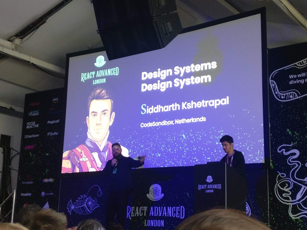 Siddharth Kshetrapal on stage with ‘Design Systems Design System’ written on a projected slide, with his avatar