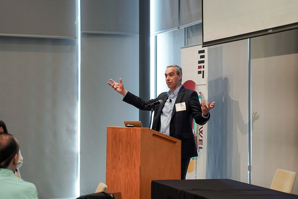 Daniel Huttenlocher speaks at a podium with an MIT banner behind him.