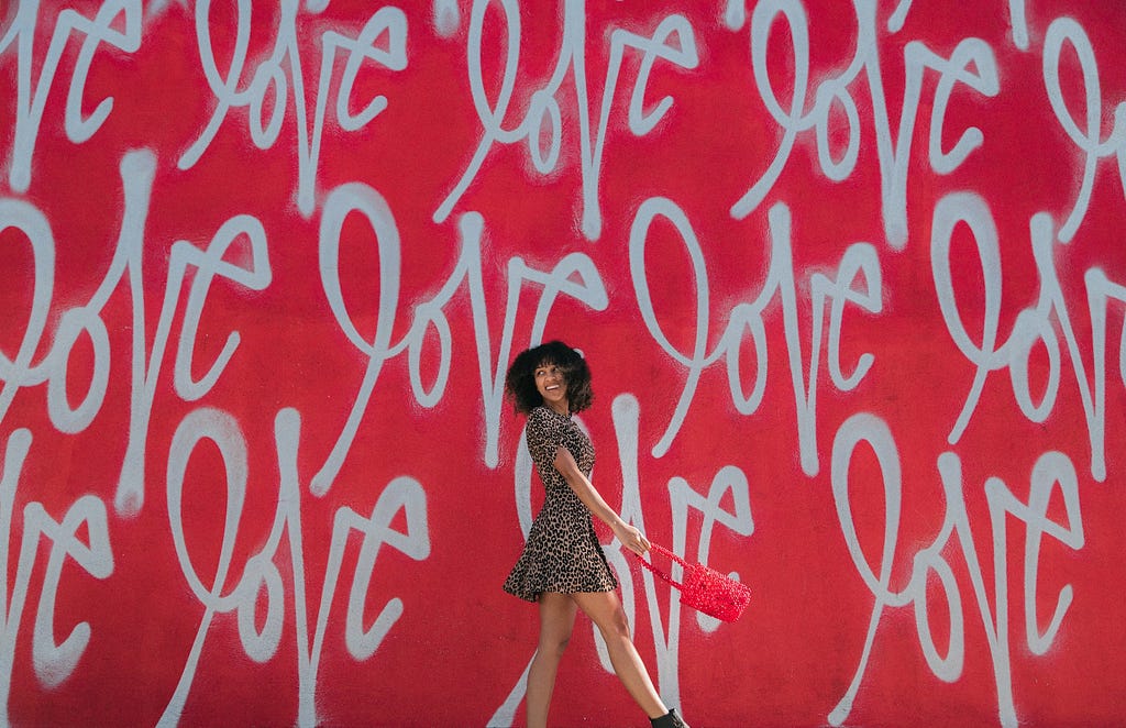 woman walking in front of wall that says love