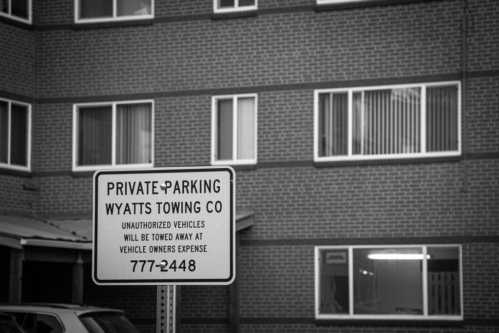 A Wyatts Towing sign in front of a multifamily apartment building