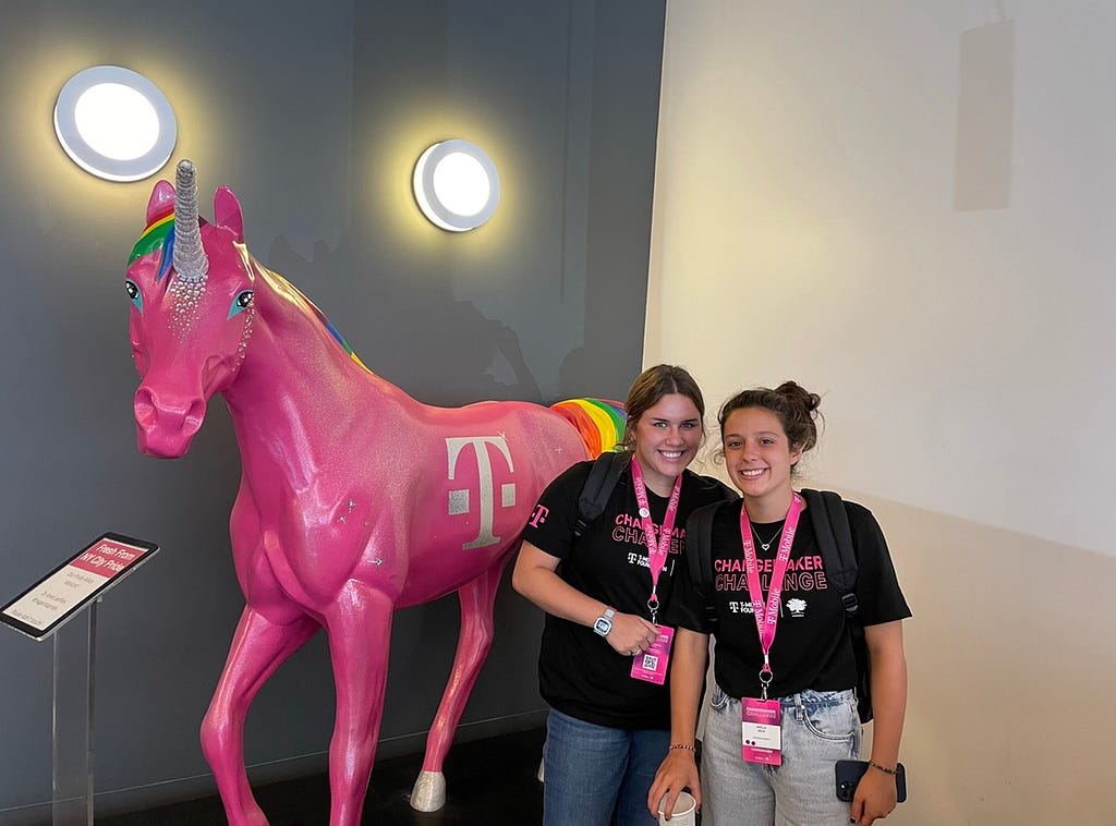 Jacqueline and Amelie at the T-Mobile Changemaker Challenge event standing next to a horse statue painted pink.