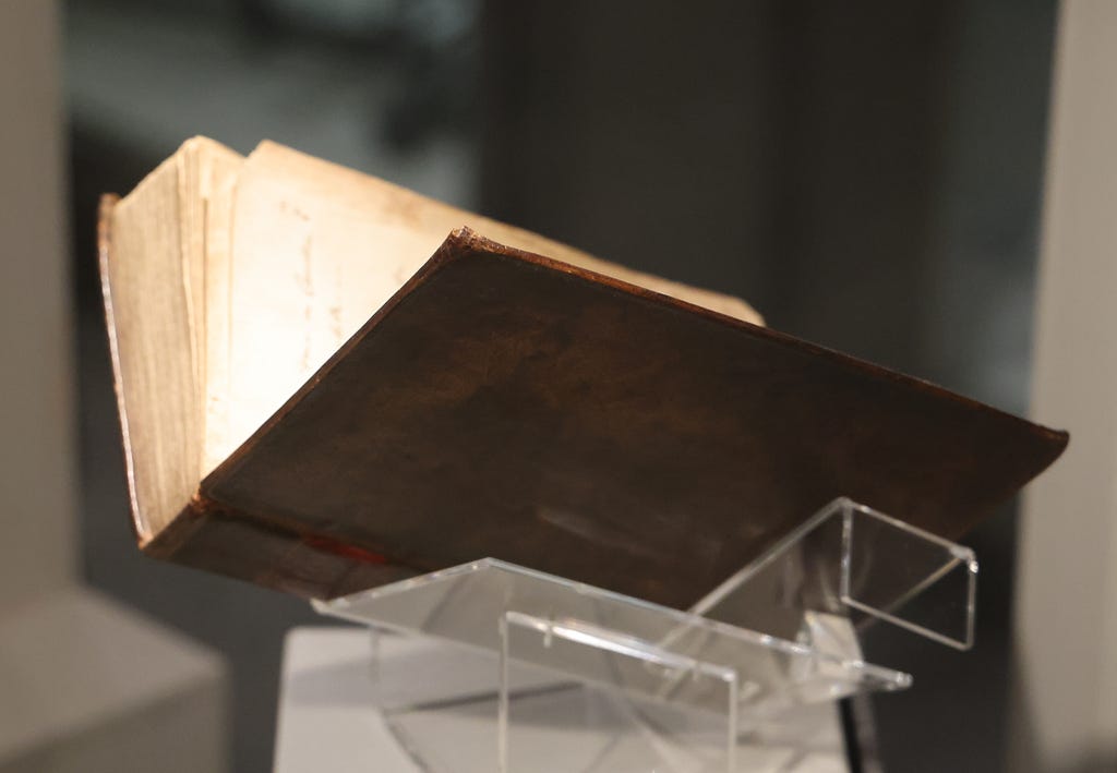 The image is a photograph of the book bound in the skin of William Corder. It lies open and the paper inside looks aged but well-preserved. The human leather looks brown and rather mundane.
