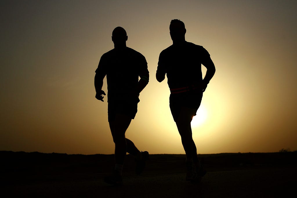 Silhouette of 2 men jogging in sunset