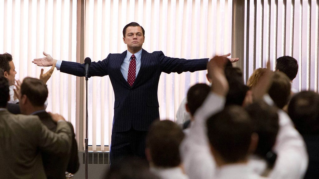 Image from Wolf of Wall Street of Leonardo DiCaprio with his arms outstretched in front of a crowd