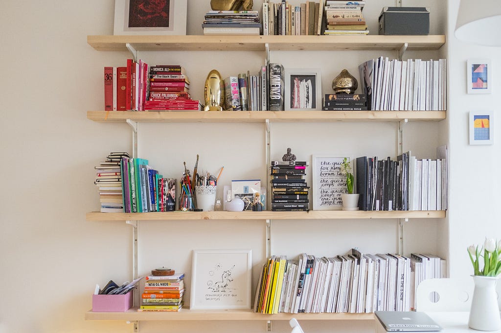 a shelf with books, stationery and figurines