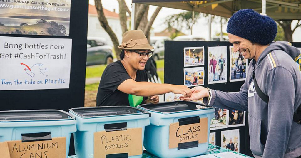 Ina from EcoMatters at a bottle drive handing coins to a smiling man