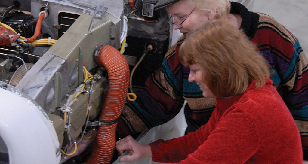 Two women working on an aircraft engine.