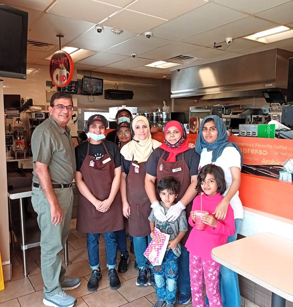 A group of women, two kids and a man standing inside a Dunkin Donut