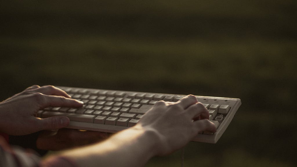 A man typing on an old white and unconnected keyboard