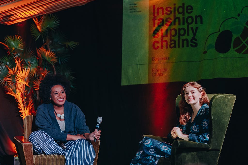 Aja Barber and Sophie Slater smiling whilst sat in armchairs during an on stage conversation.