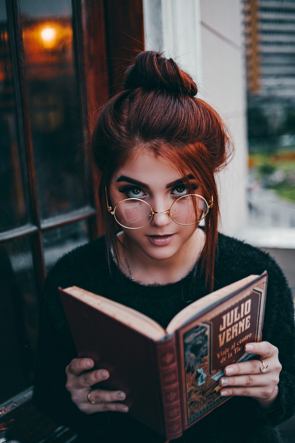 Young woman holding a book in her hand while looking into the camera