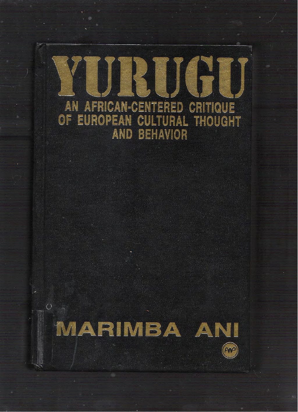 Livro de capa preta e letras douradas com o título “Yurugu”.