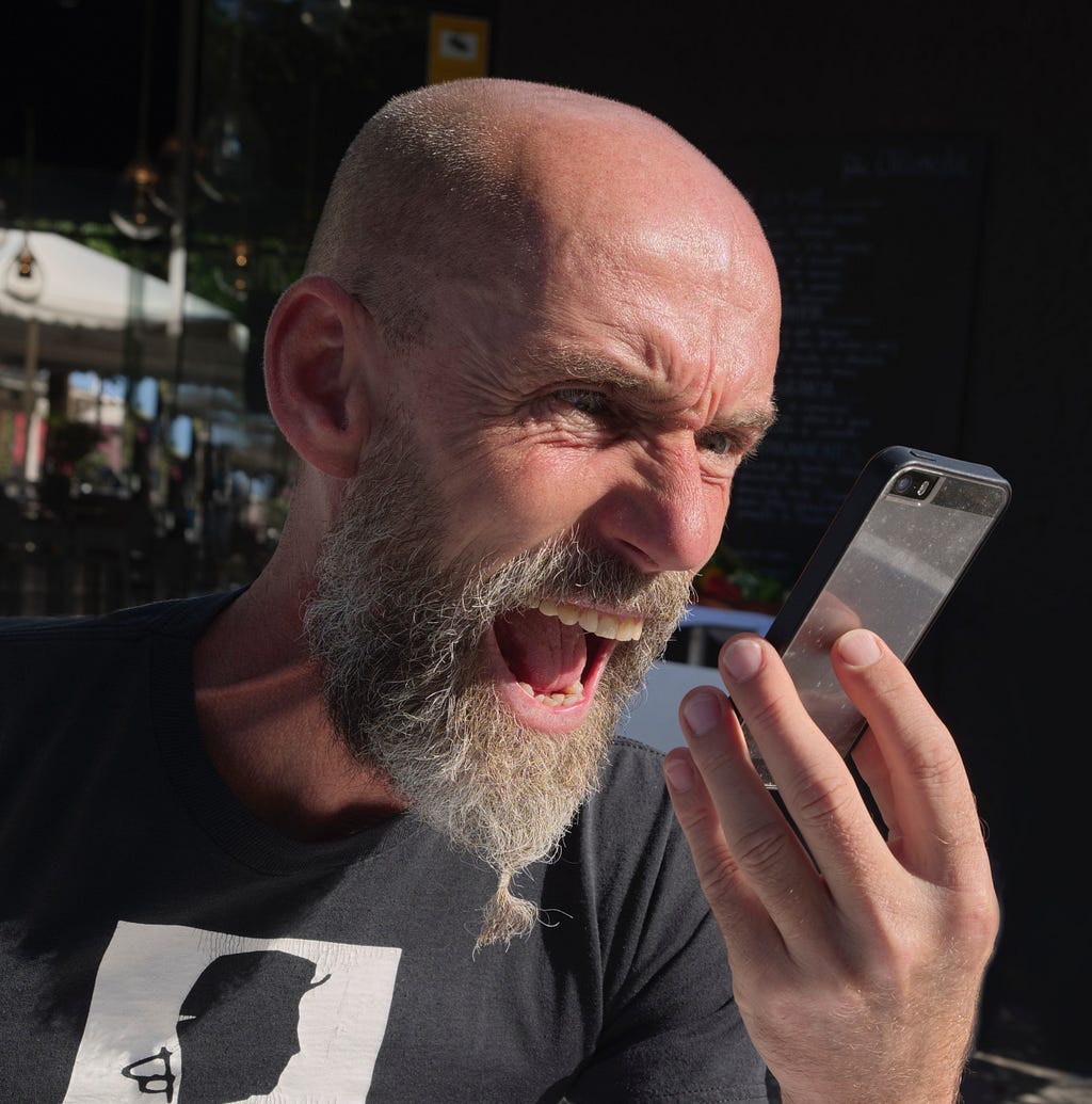 A man shouting angerly at his smartphone.