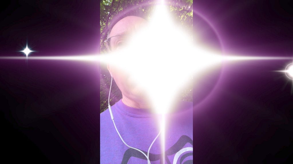 A bright starburst graphic partially obscuring an image of me wearing earbuds. The starburst, which represents sensory overload, is paired with my imitation of a loud motorcycle at the end of the video linked below.