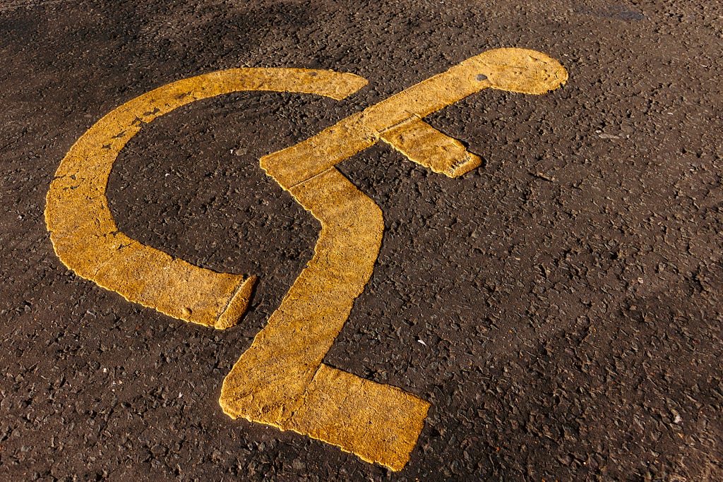 a close-up of a wheelchair sign painted on asphalt