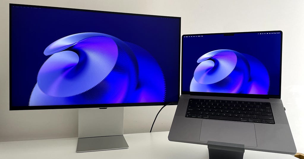 The Samsung monitor on the left, with a 16″ M1 MacBook Pro connected to its right.
