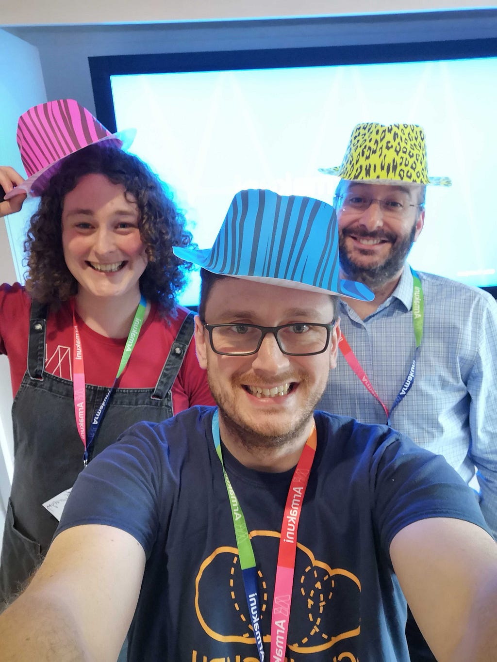 3 people from the  Armakuni team wearing silly party hats at an Agile conference