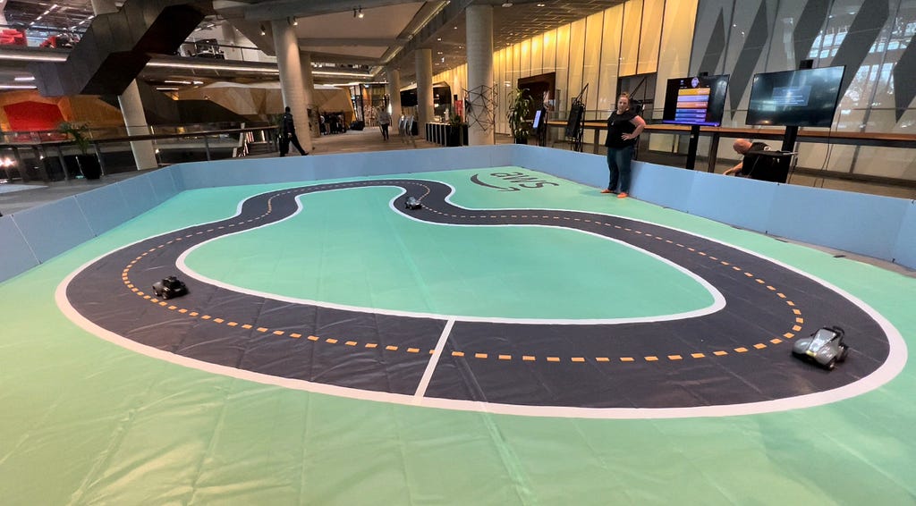 A miniature-sized car racing track with a single loop of road with remote control cars moving in the same direction.