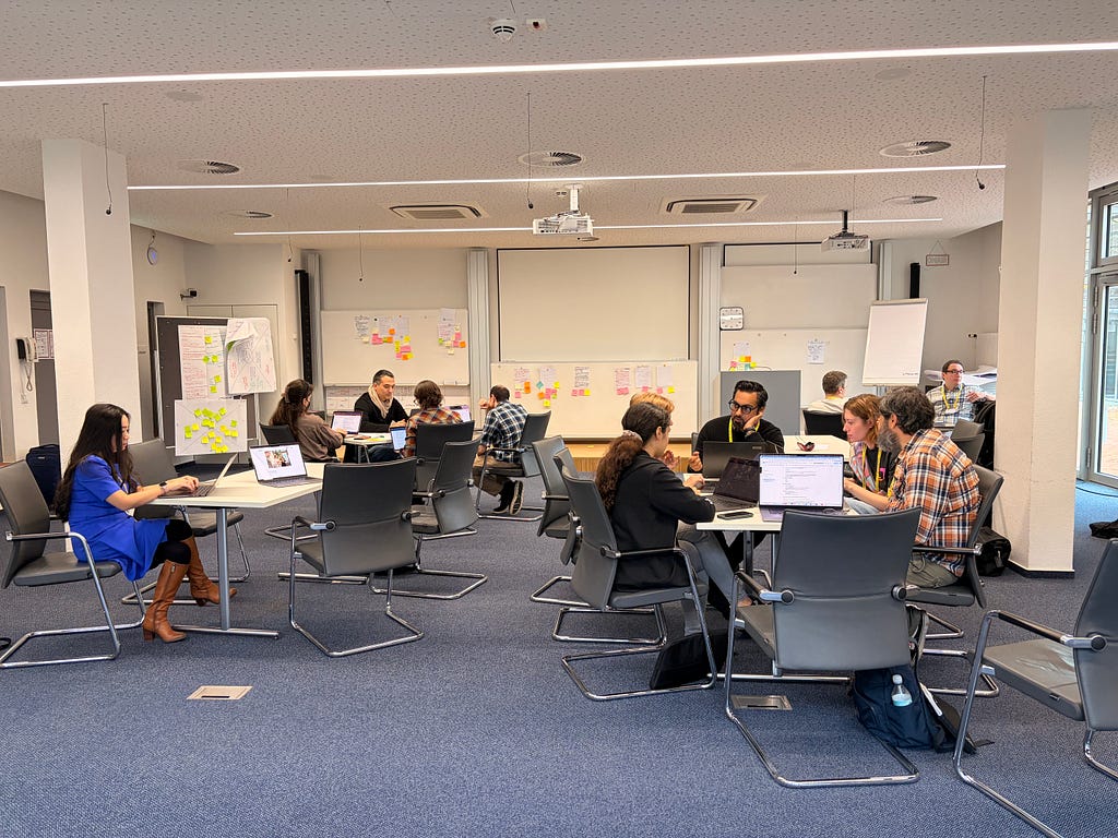 A room, tables, chairs, and many people quietly talking and writing.