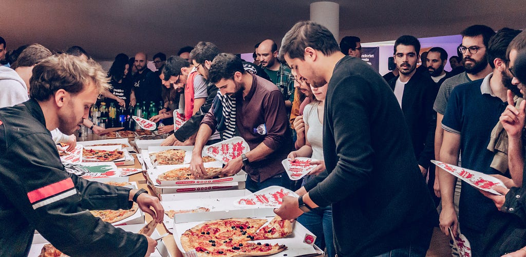 Crowd grabbing pizza from a big table