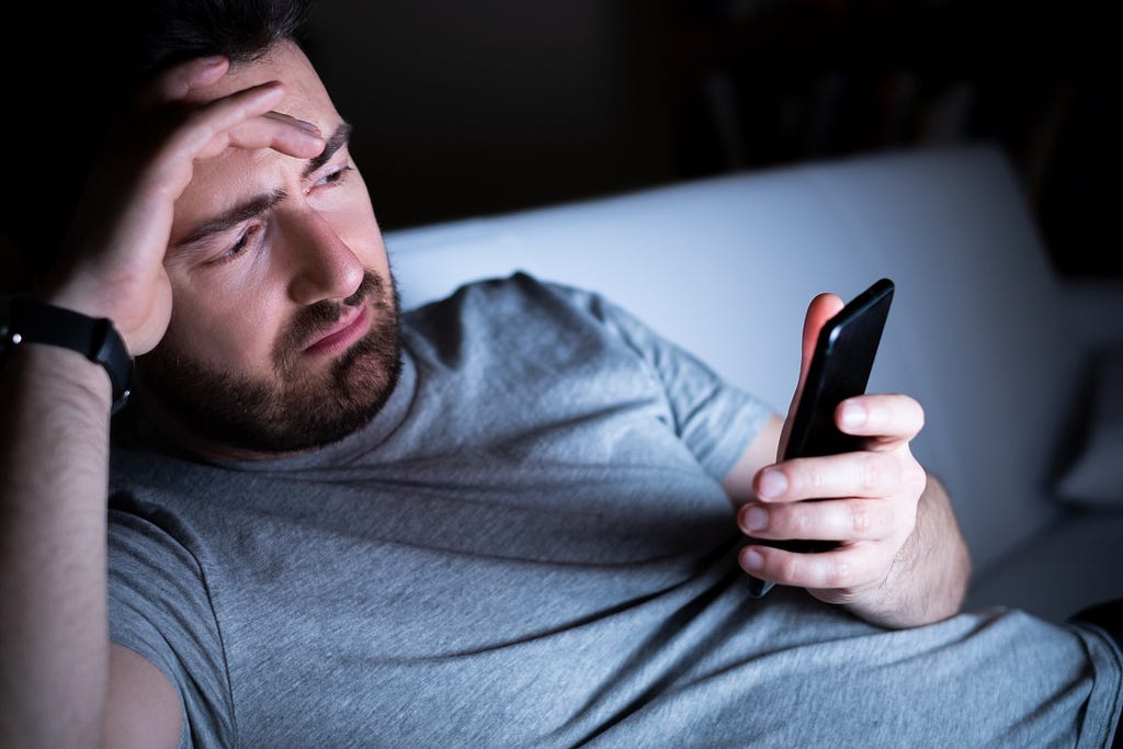 Man feeling depressed using phone at night