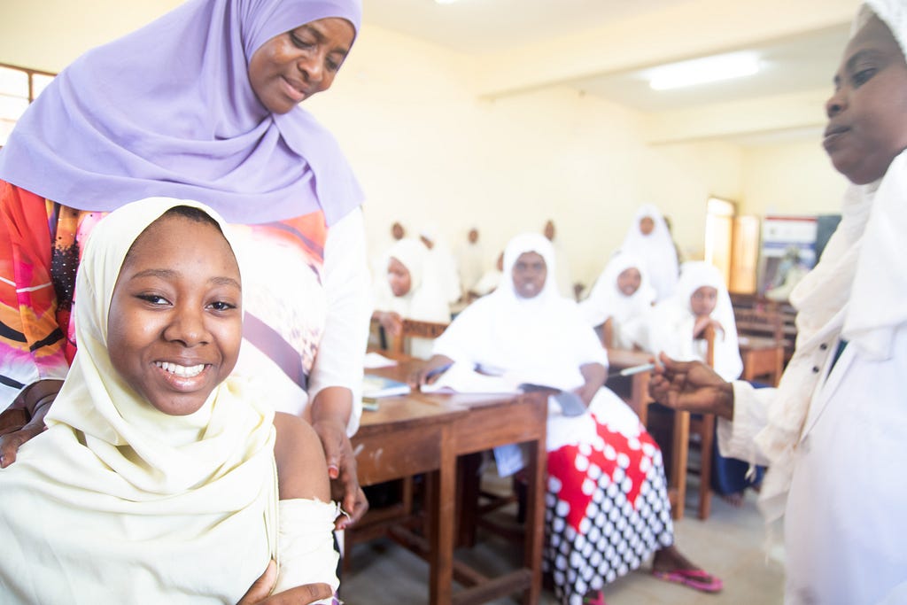 Student at Donge School in Zanzibar smiling at the camera after receiving her HPV vaccine from a health worker.