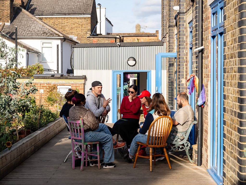 Members of South Norwood Community Kitchen sit in a sunny garden and discuss shared issues.