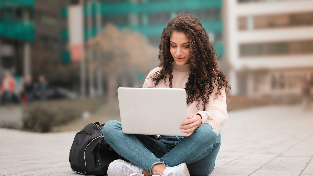 college student outside using laptop