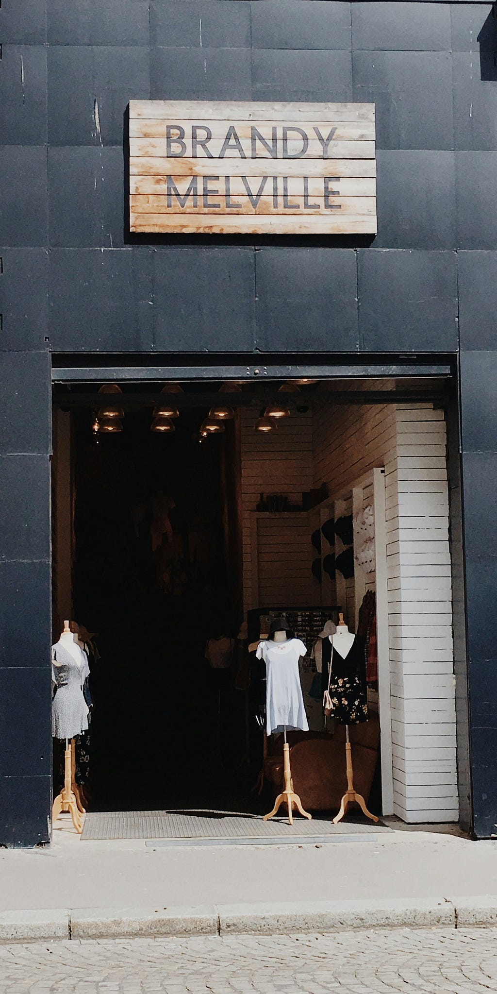 Image of the front of a Brandy Melville store, complete with sign and mannequins with clothed in store items