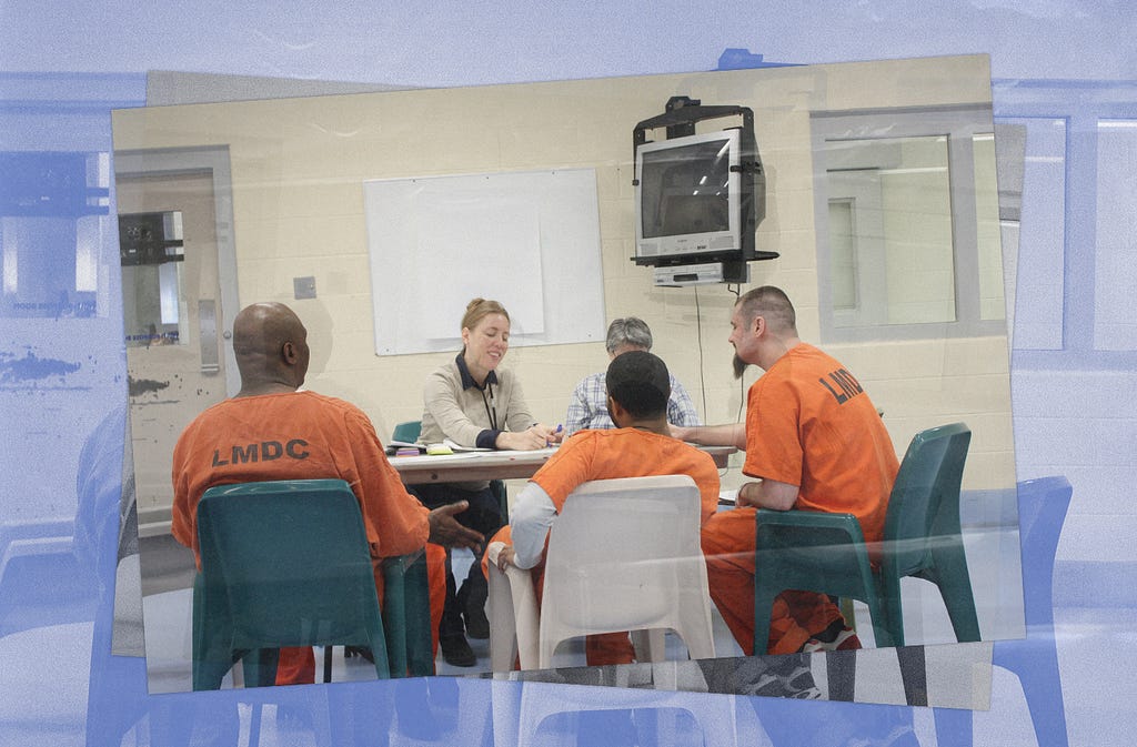 Two researchers sit at a table with incarcerated people at the Louisville Metro Government Jail.
