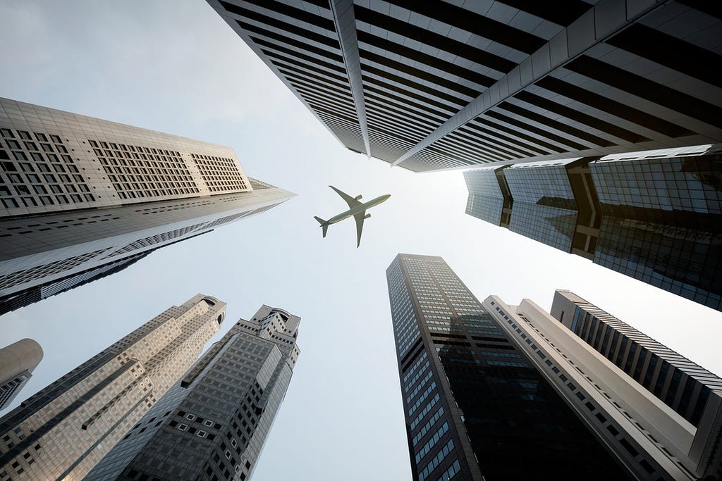Airplane flying over city buildings.