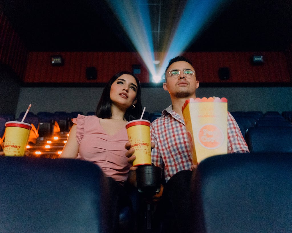 A couple watching a movie in the theatre with great interest