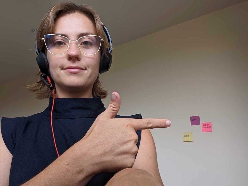 A person pointing to three sticky notes on a wall.