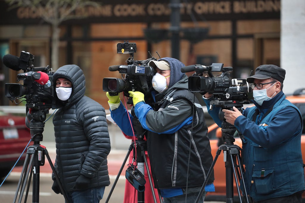 Journalists wearing masks and using cameras to document a protest in Chicago, IL
