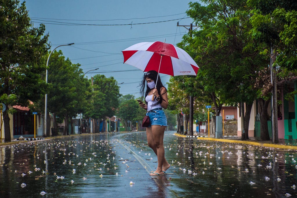 a woman with a cell phone walks connected to the Internet on a street in Cuba.