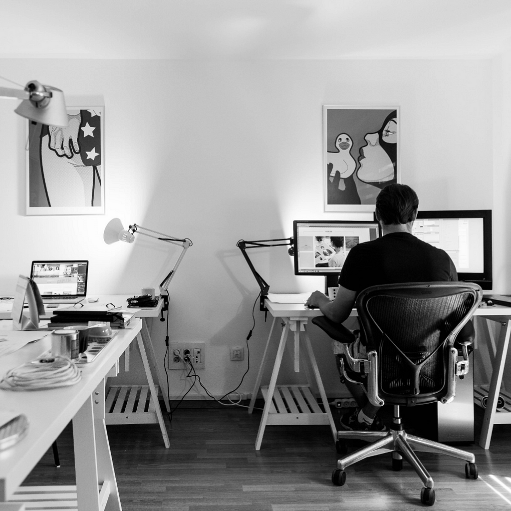 A black and white photo of a web designer in his studio or office and working.