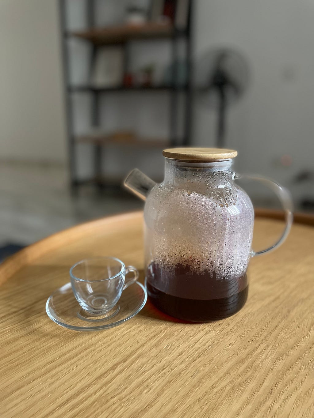 A glass jug with a wooden lid and a glass tea cup