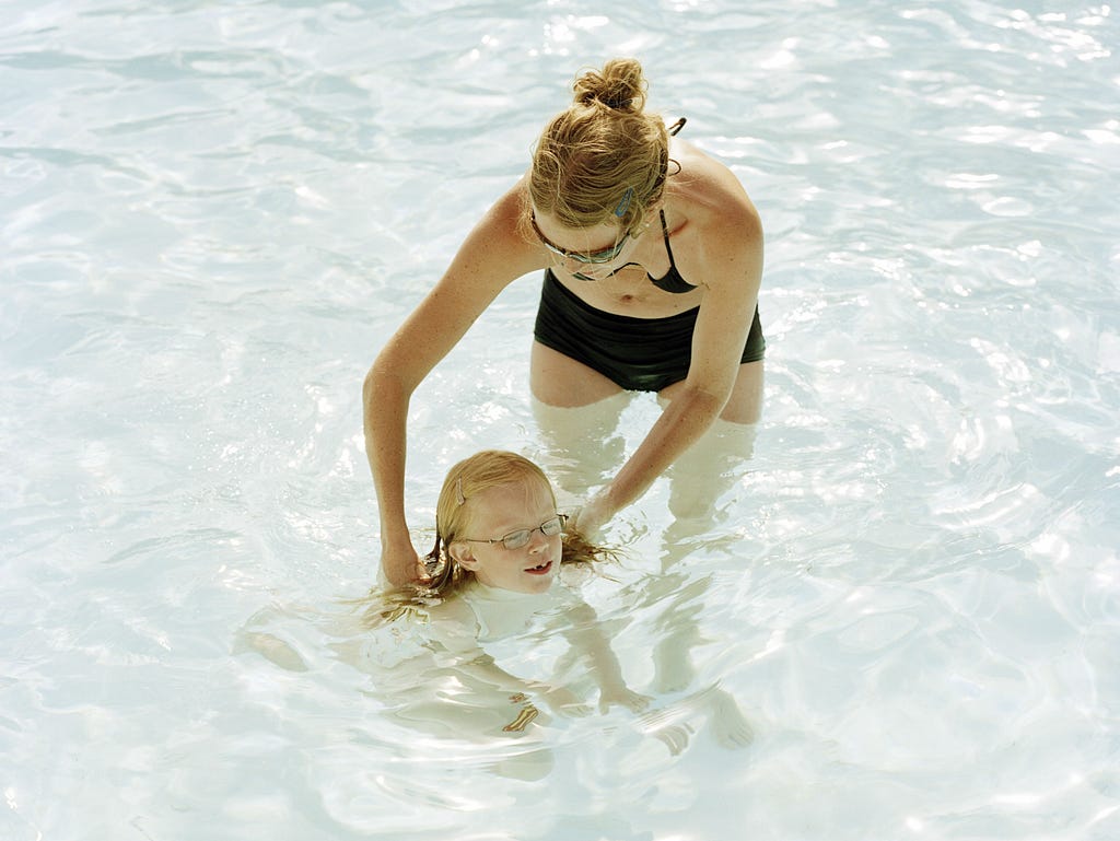 A mother teaching her daughter to swim.