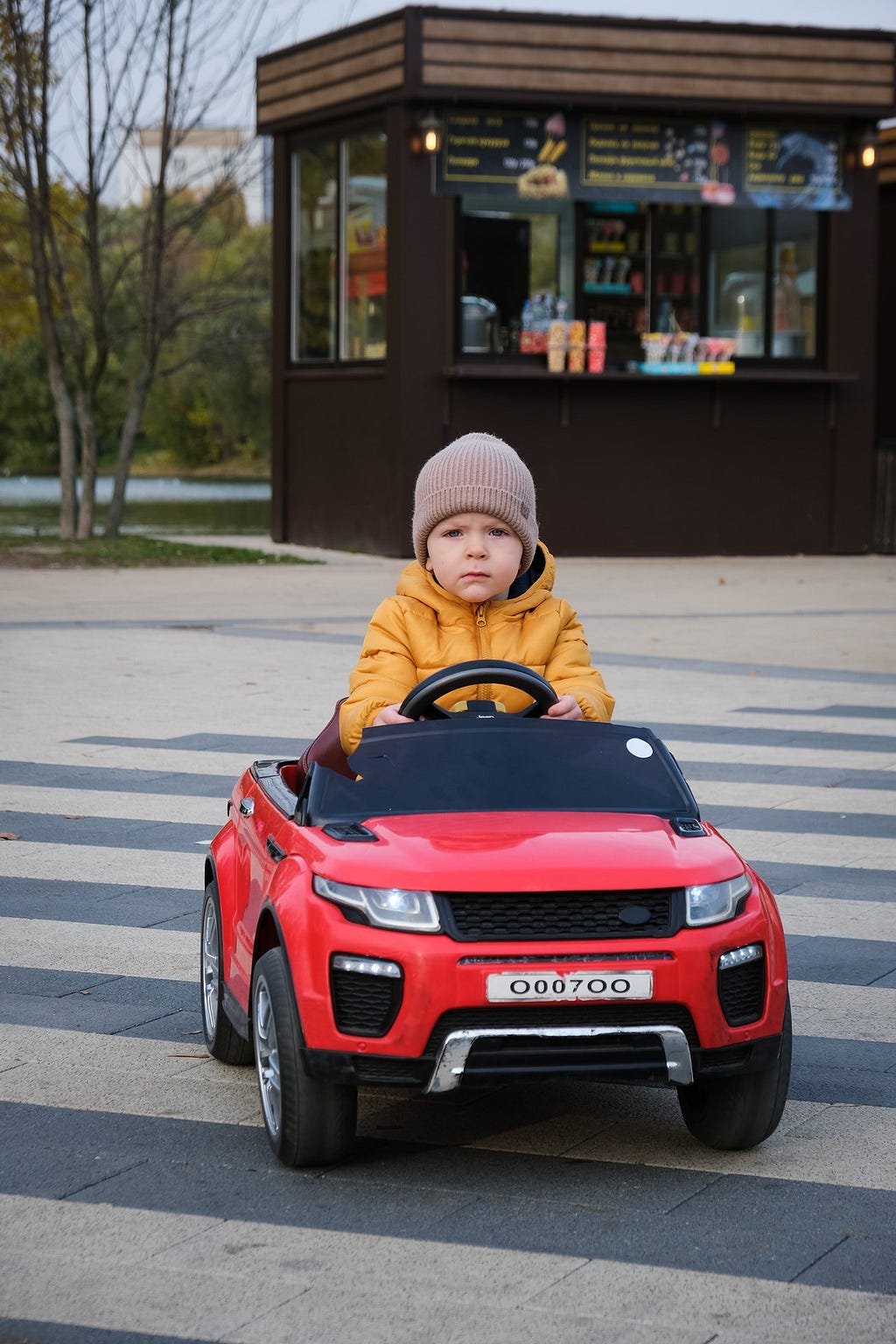 A child is driving a miniature toy car.