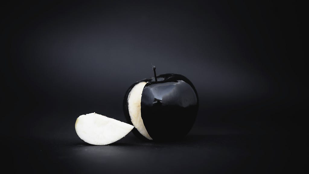 A slice cut off from a black colored apple