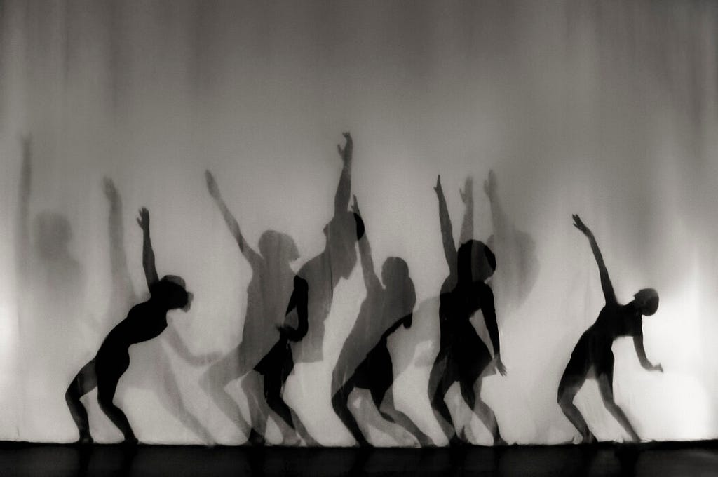 Shadows of dancers behind a translucent curtain.