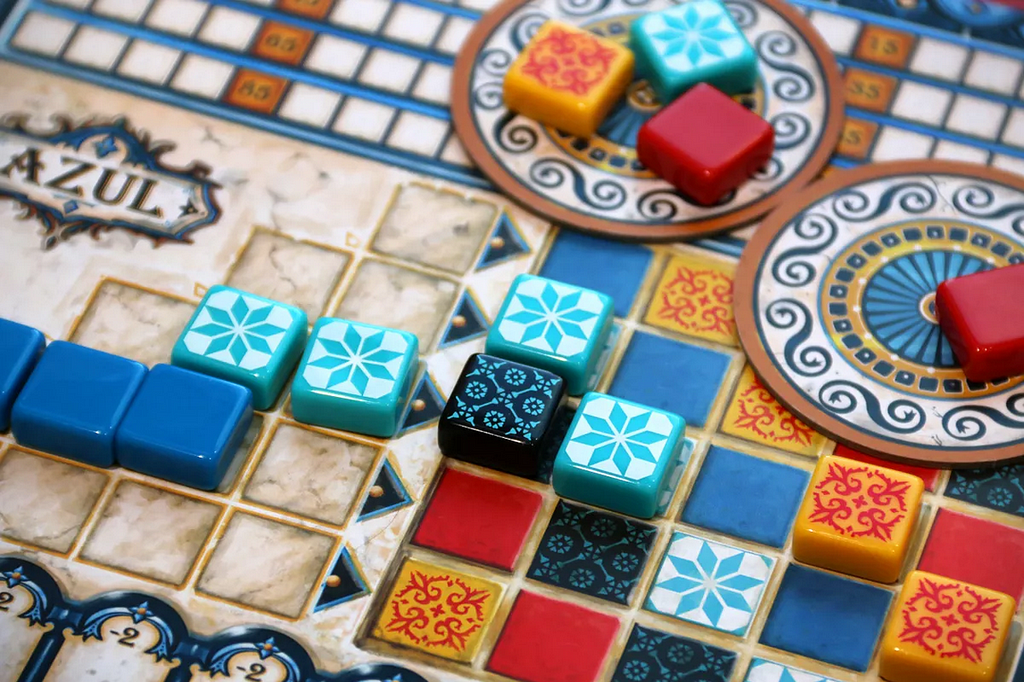 Decorative image of the board game Azul. Components are place into sections that match their color, generally.