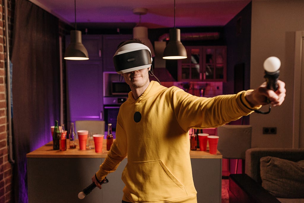 A teenager in yellow hoodie playing with VR game headset in living room.