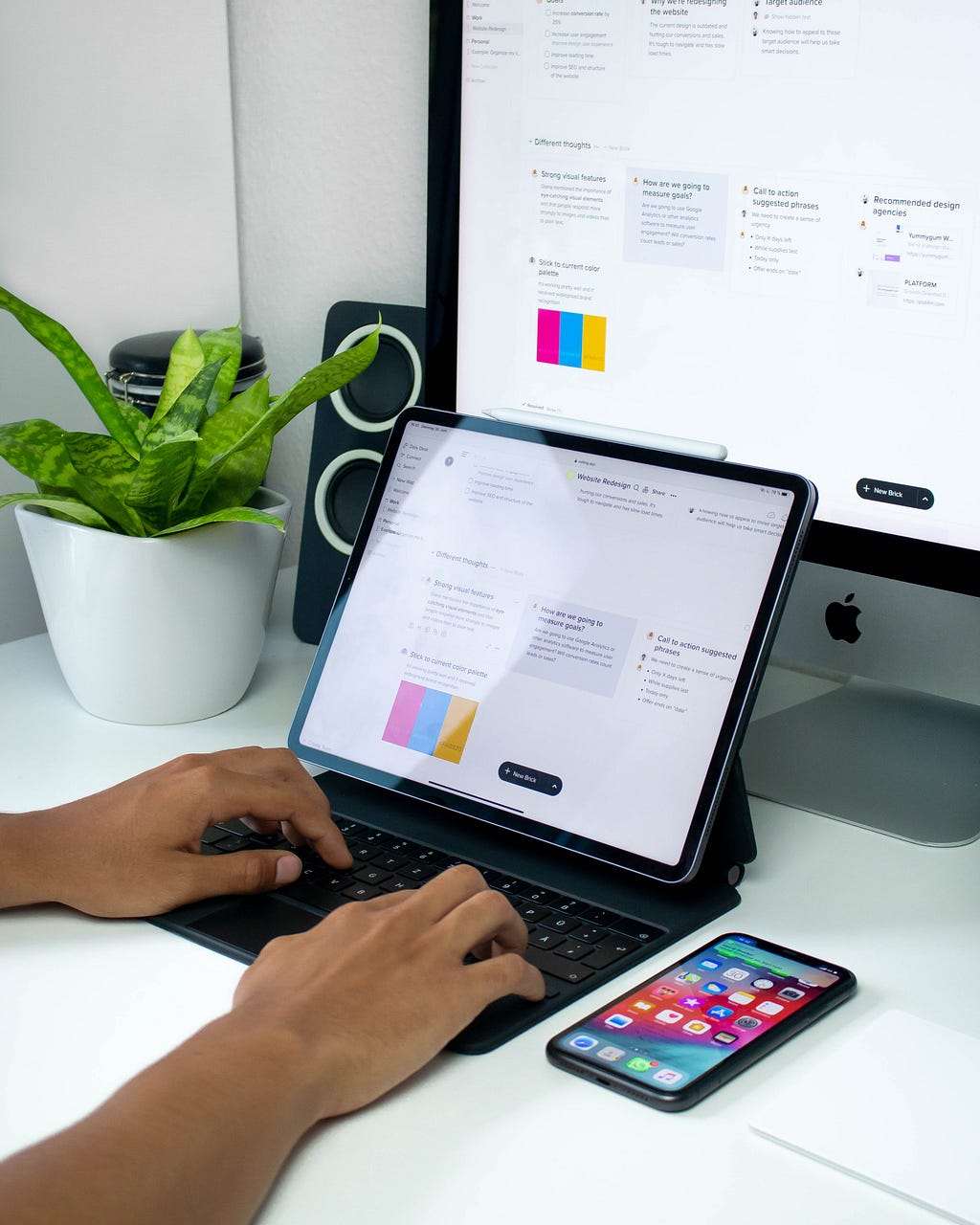 A person working on a project using a tablet on a well-organized desk.