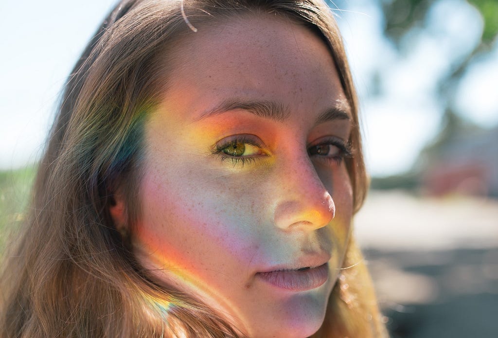Woman with rainbow light on face.